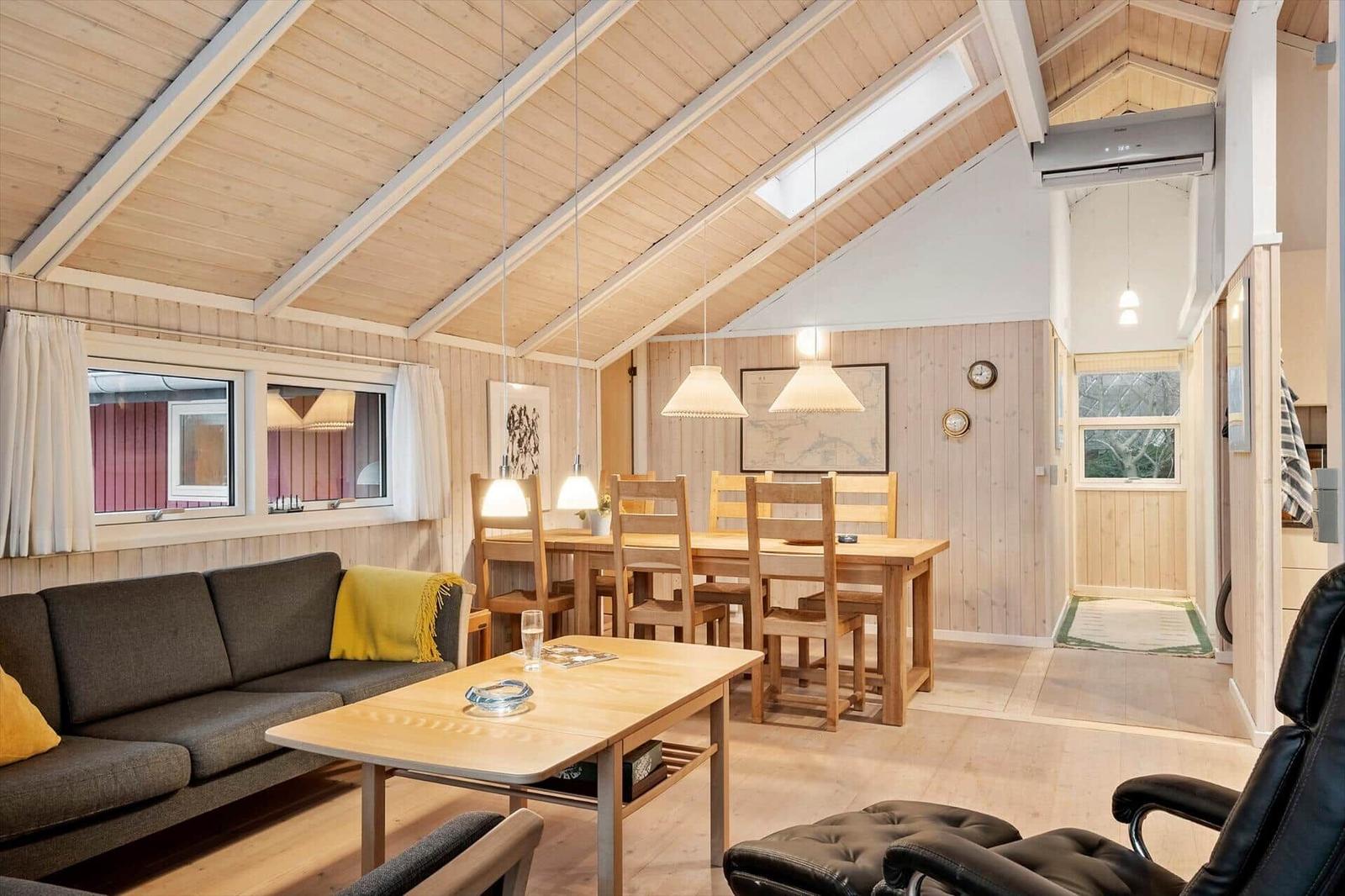 Wohn- und Essbereich mit Holzdecke, Sofa, Tisch und Stühlen.