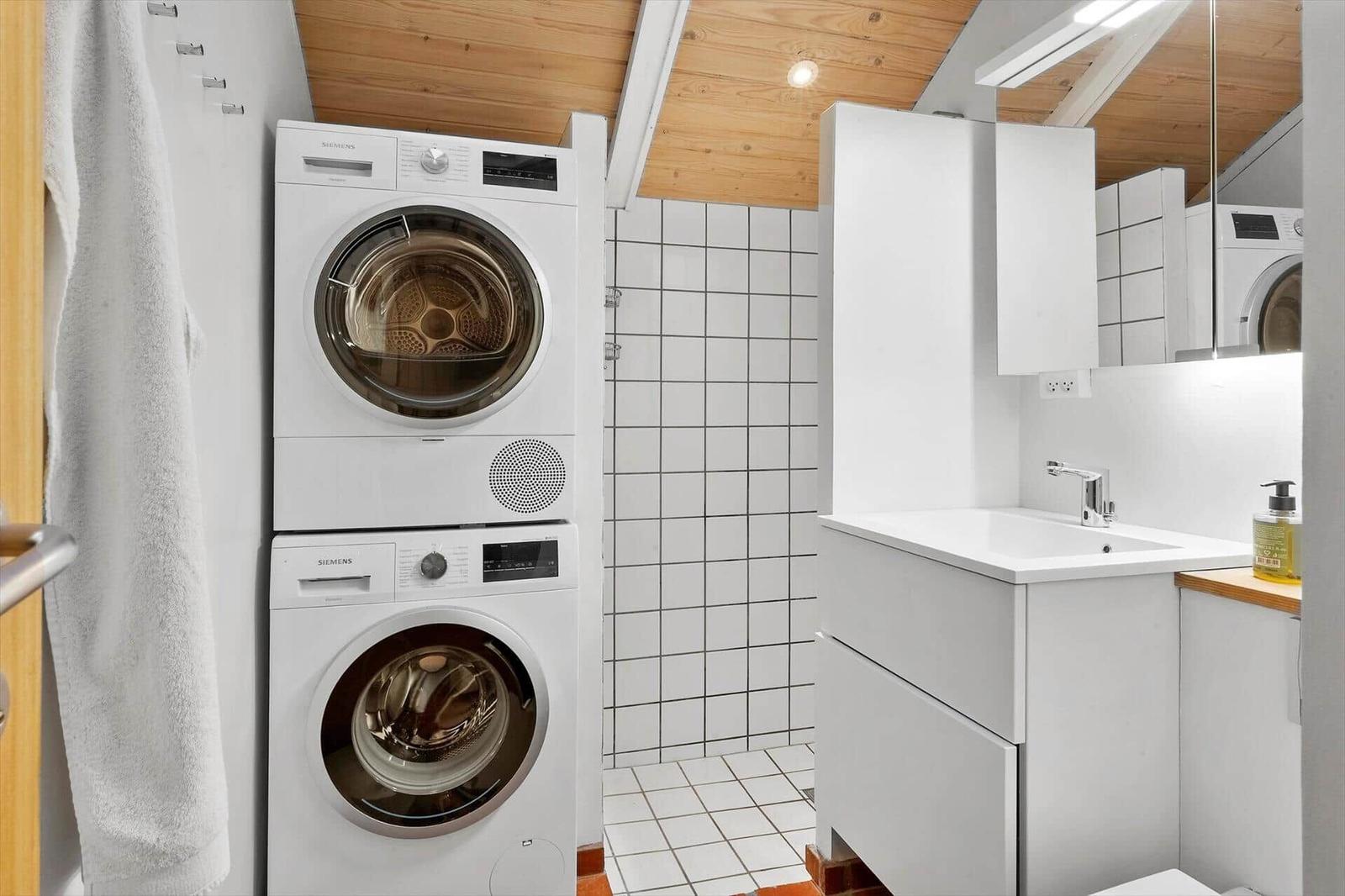 Wohnung mit Waschmaschine und Trockner sowie Waschbecken und Spiegel.