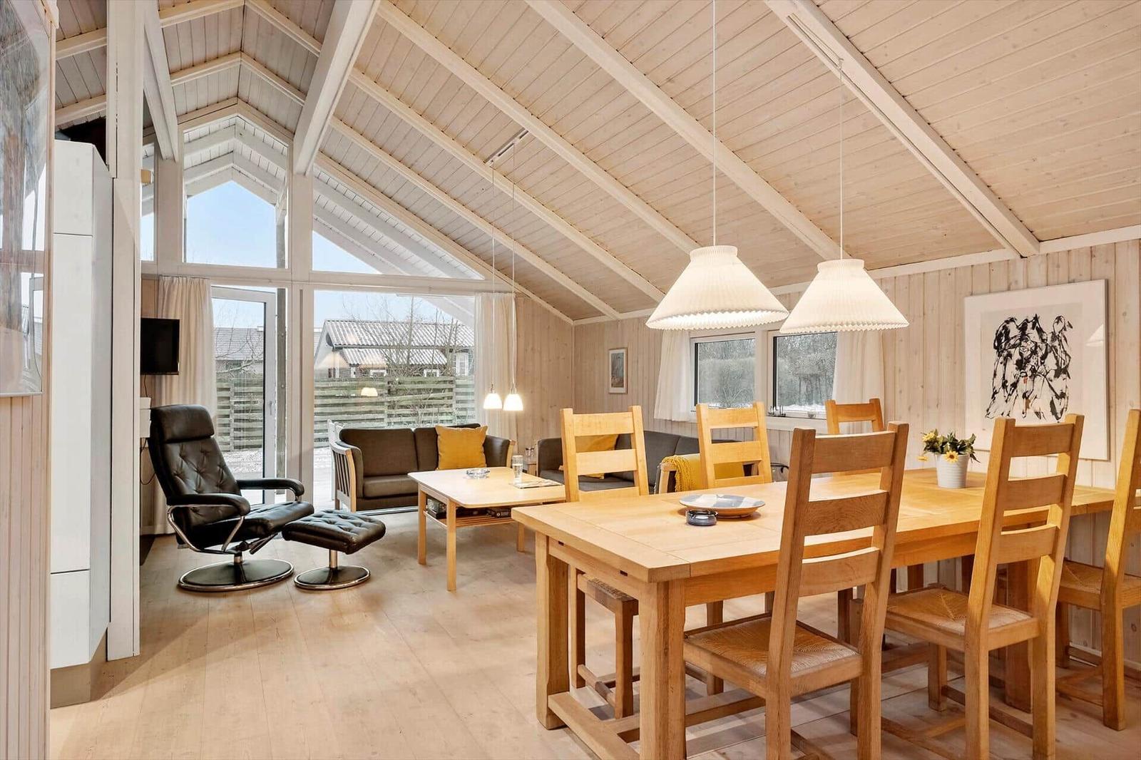 Haus mit Essbereich und Wohnbereich unter hohem Dach mit Holzverkleidung und Fenstern.