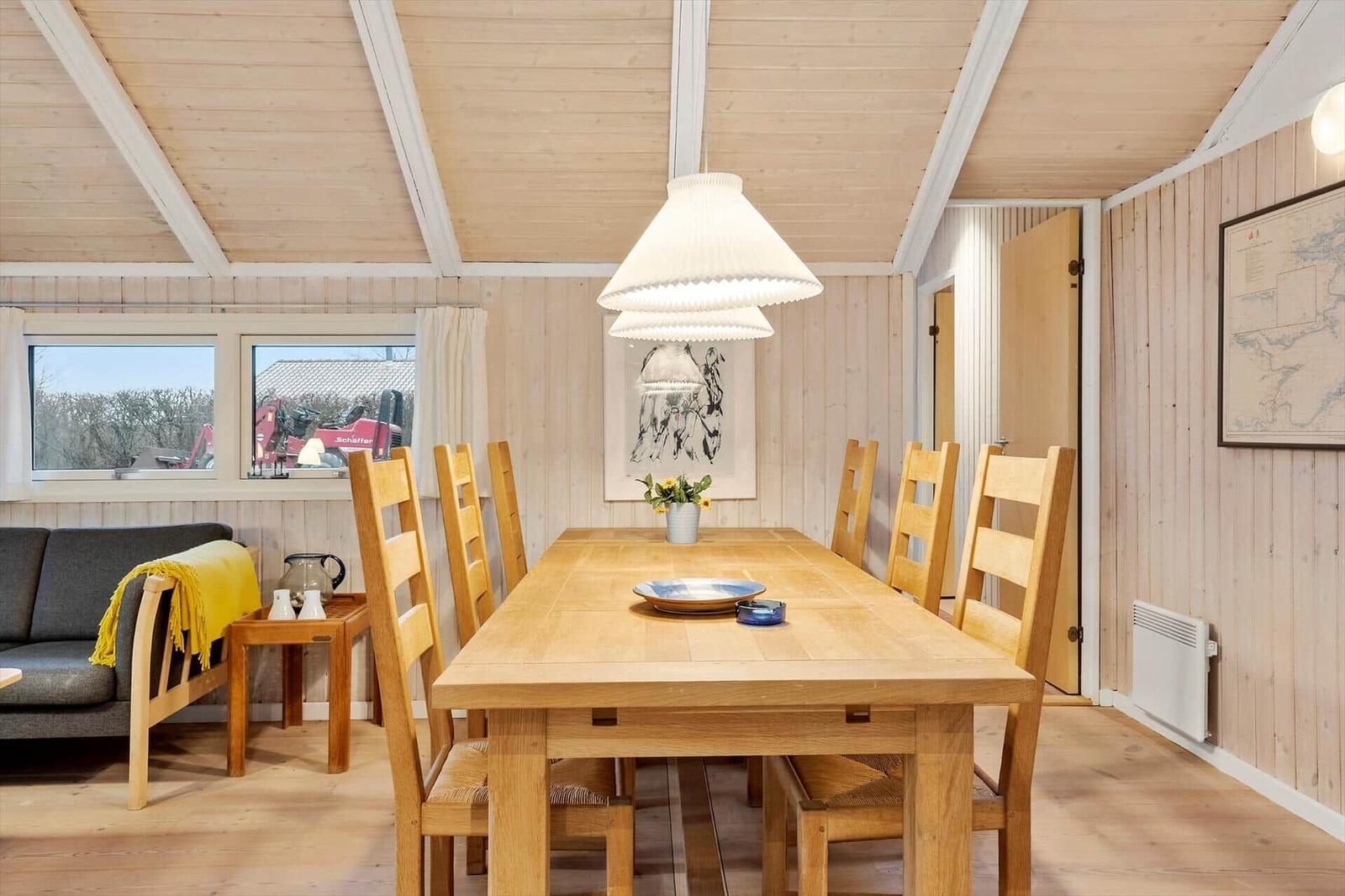 Esszimmer mit Holztisch, Stühlen und Fenster. Decke und Wände sind holzverkleidet.