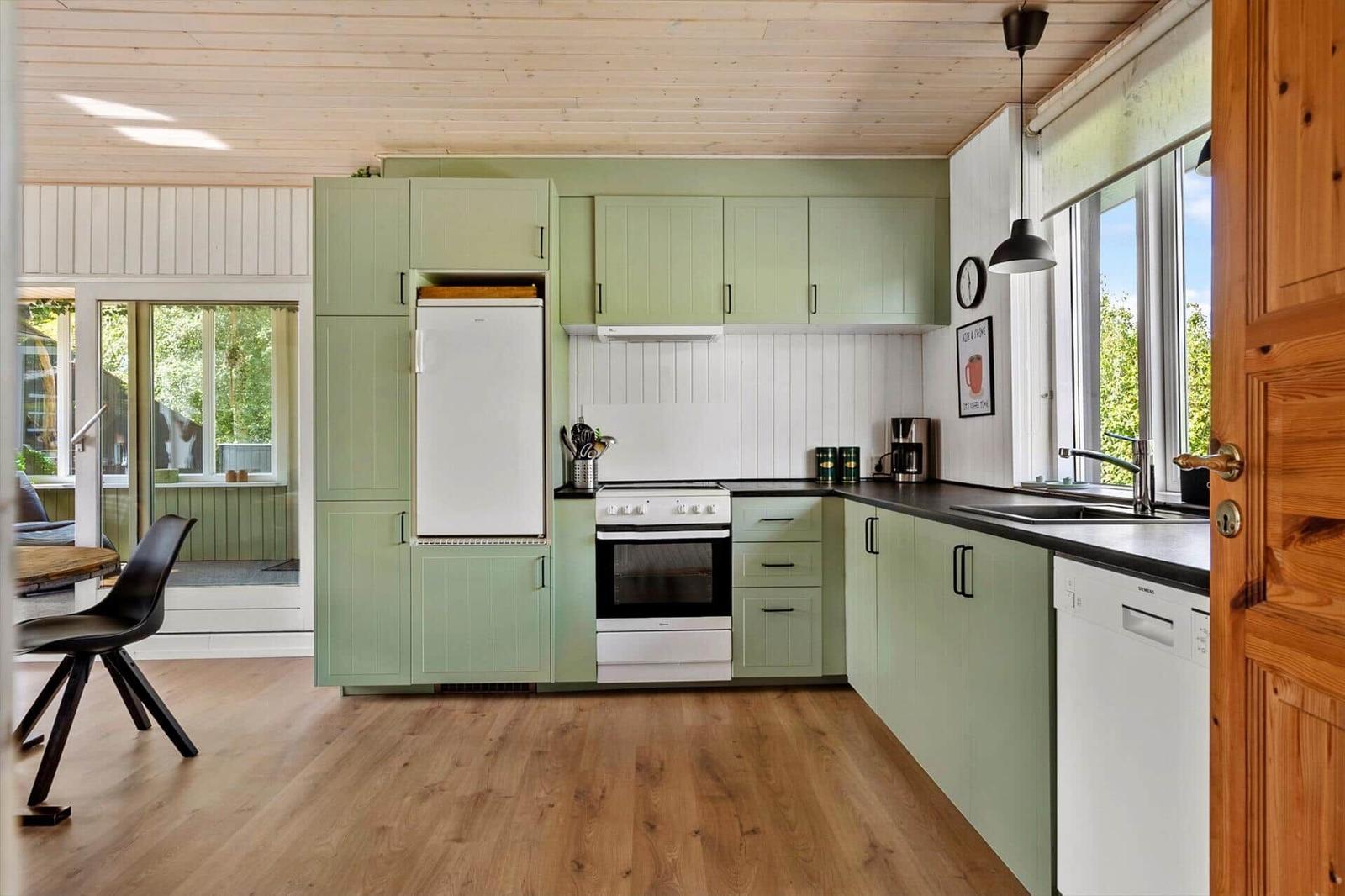 Kitchen with green cabinets, white stove, and black countertop.