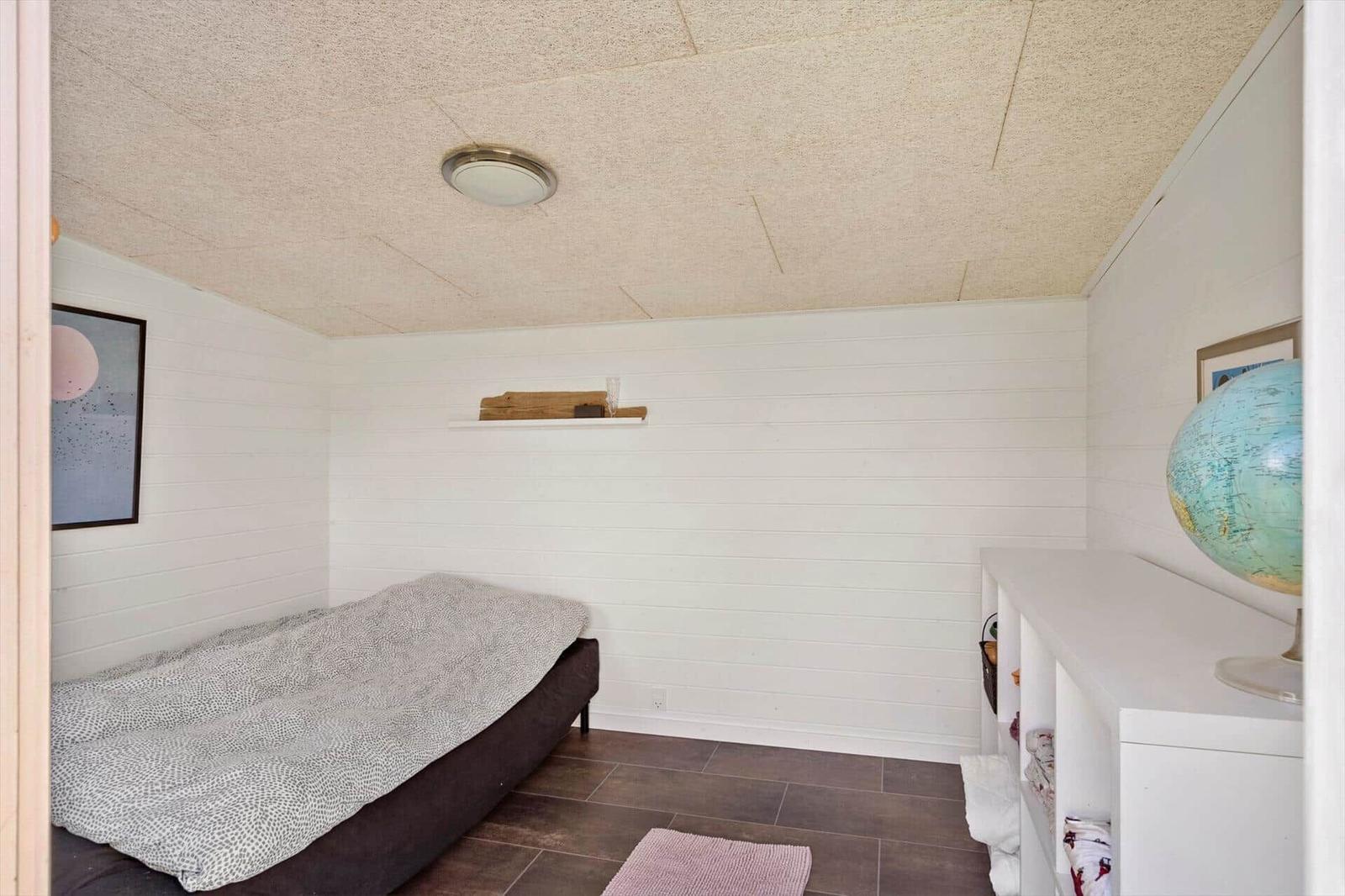 Bedroom with bed, globe, and white walls.