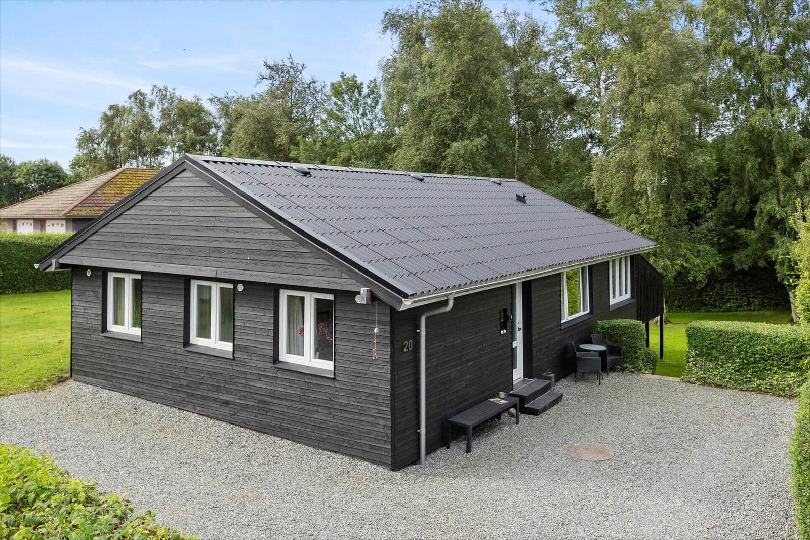 Black wooden house with white windows and garden area