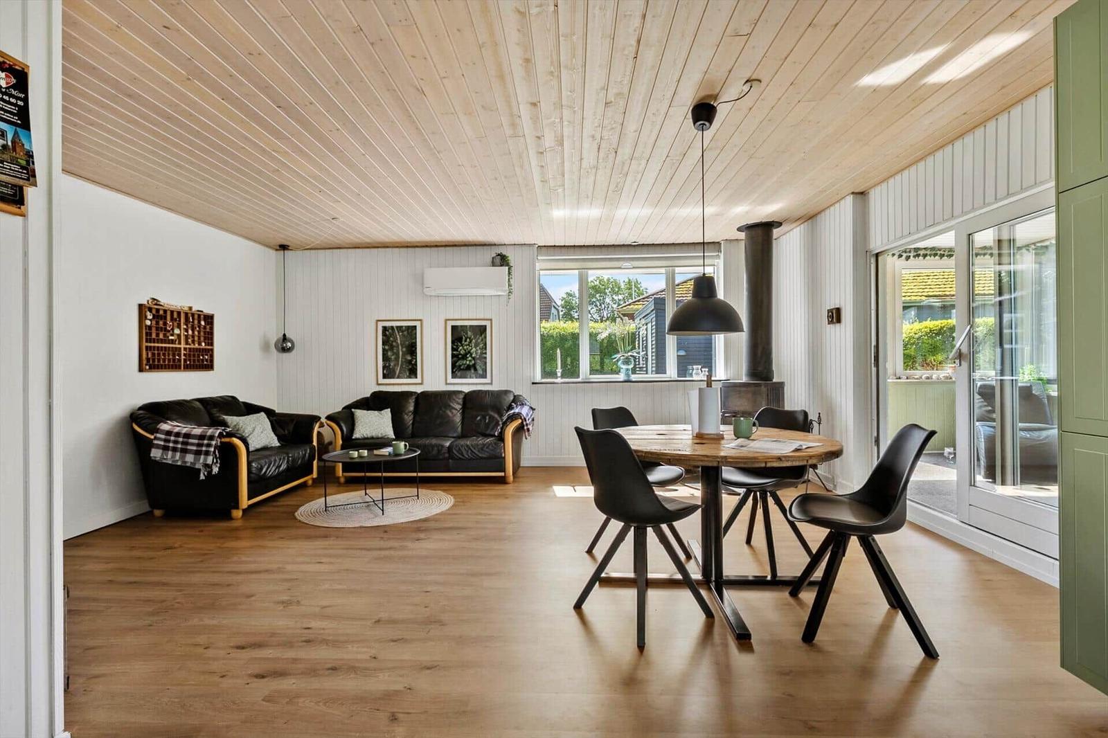 Living and dining area with wooden floor, sofa, dining table, and windows.