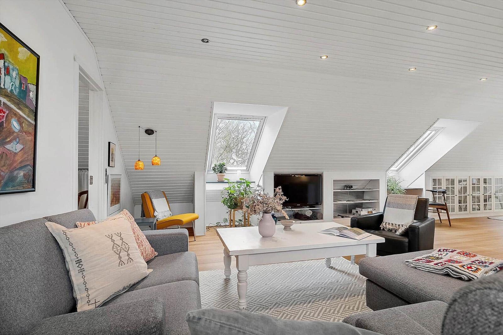 Wohnzimmer mit grauem Sofa, weißem Couchtisch und Dachfenstern.