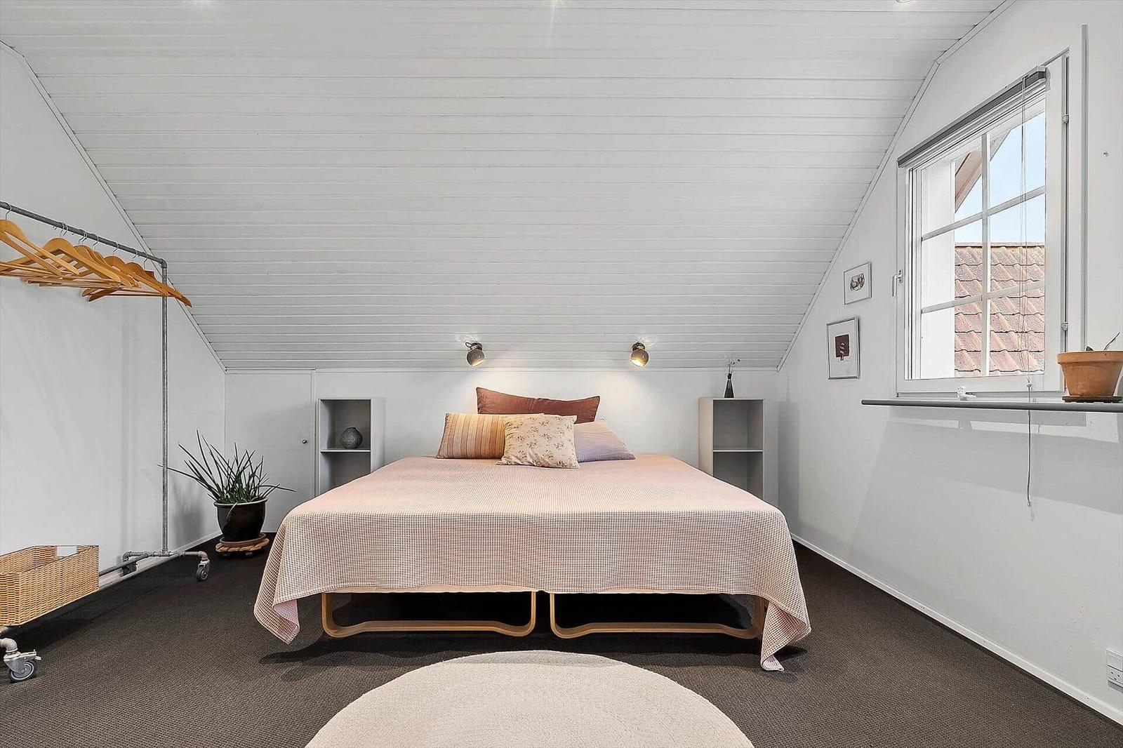 Schlafzimmer mit Bett, Kleiderständer und Fenster