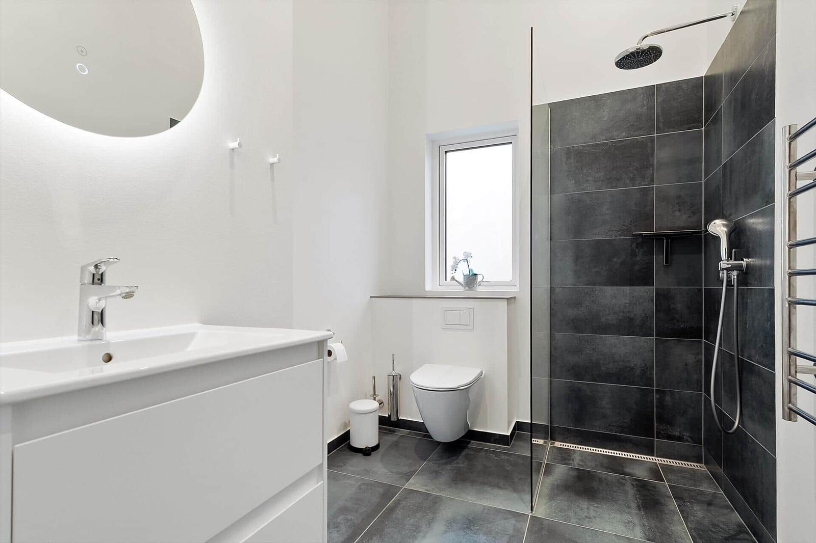 Badezimmer mit Dusche, Waschbecken und Toilette.