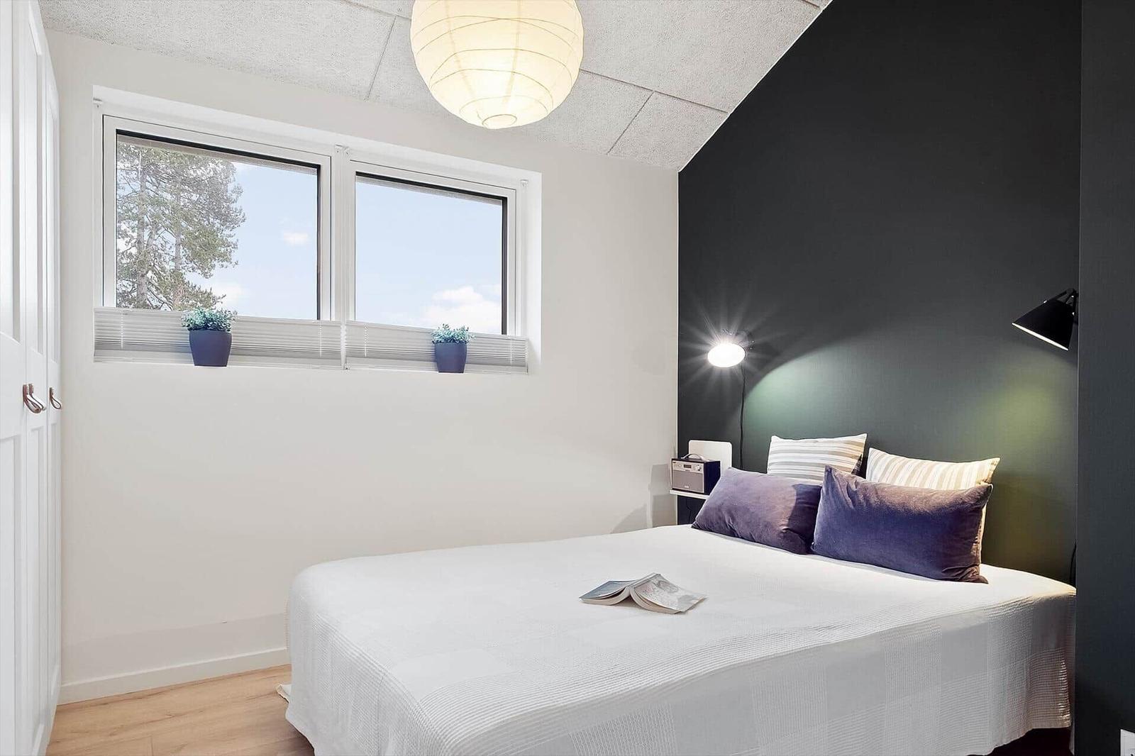 Schlafzimmer mit Bett, Fenster und Lampen.