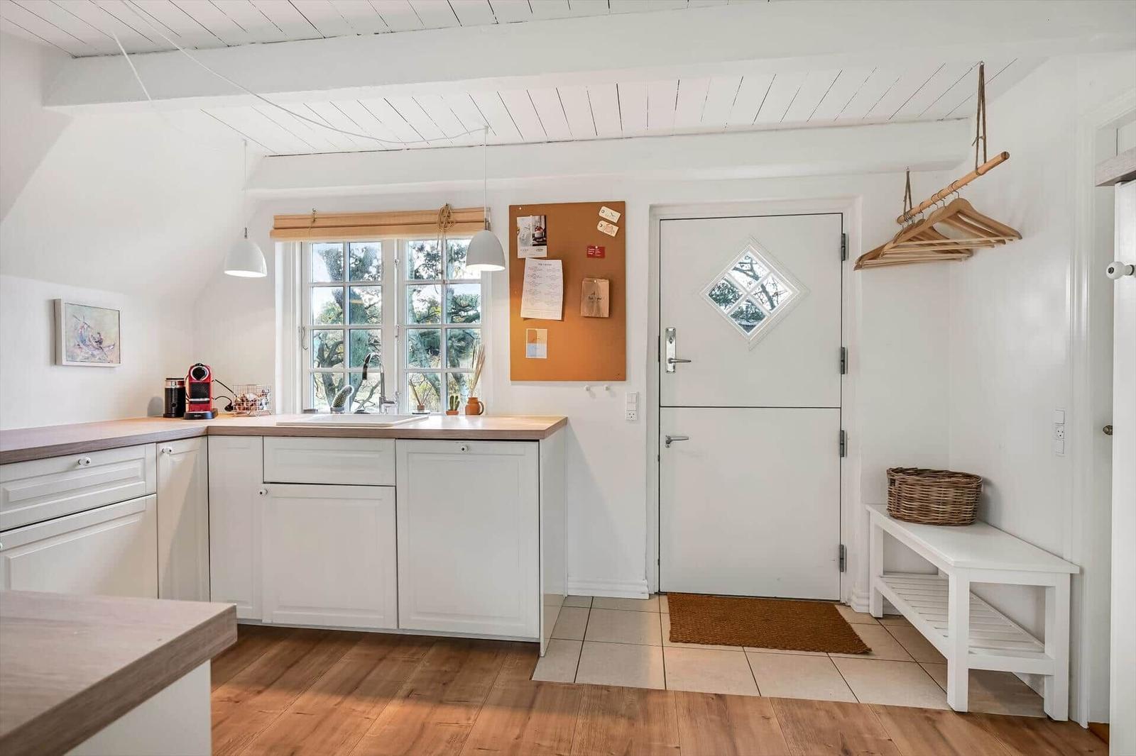 Küche mit Holzboden, weißer Tür und Holzbank.