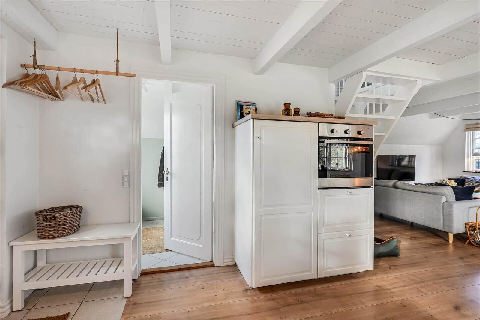 Eingangsbereich mit Garderobe, Schuhschrank und Küchenzeile mit Ofen.