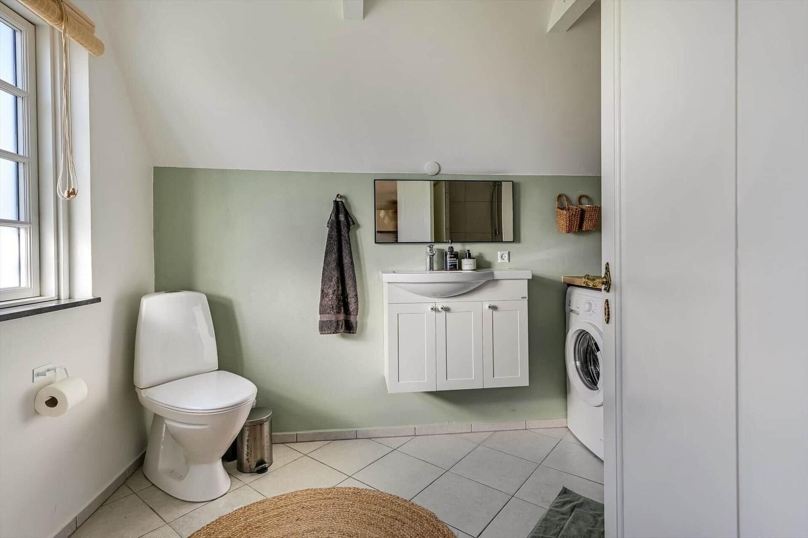 Badezimmer mit Toilette, Waschbecken und Waschmaschine.