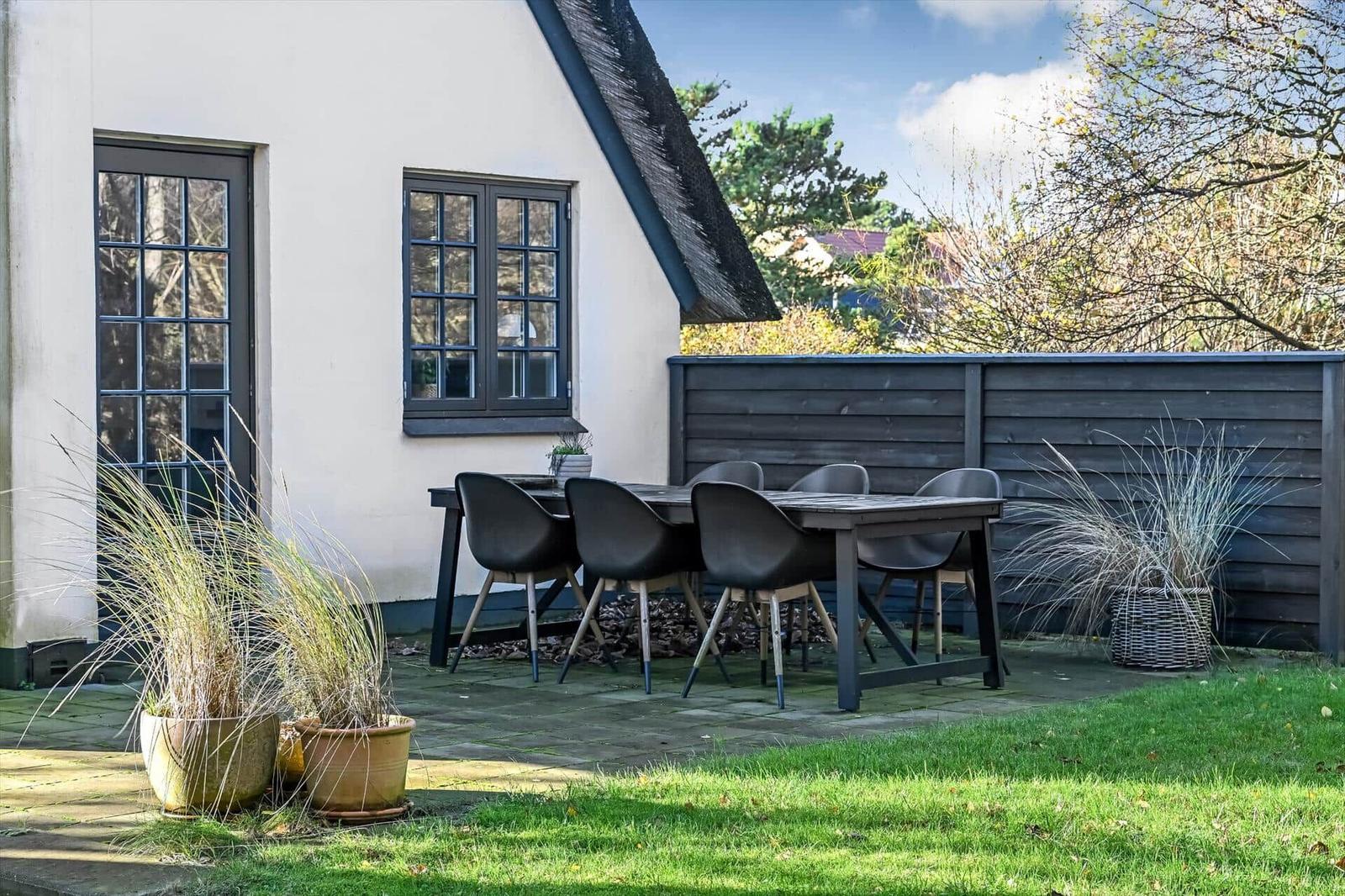 Terrasse mit Tisch und Stühlen vor einem Haus mit Schieferdach.