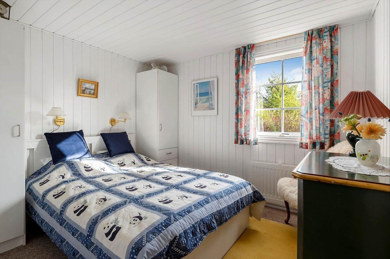 Bedroom with bed, wardrobe, and window with curtains.