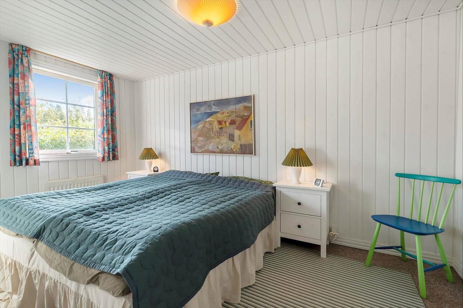 Bedroom with bed, nightstand, chair, and window with curtains.