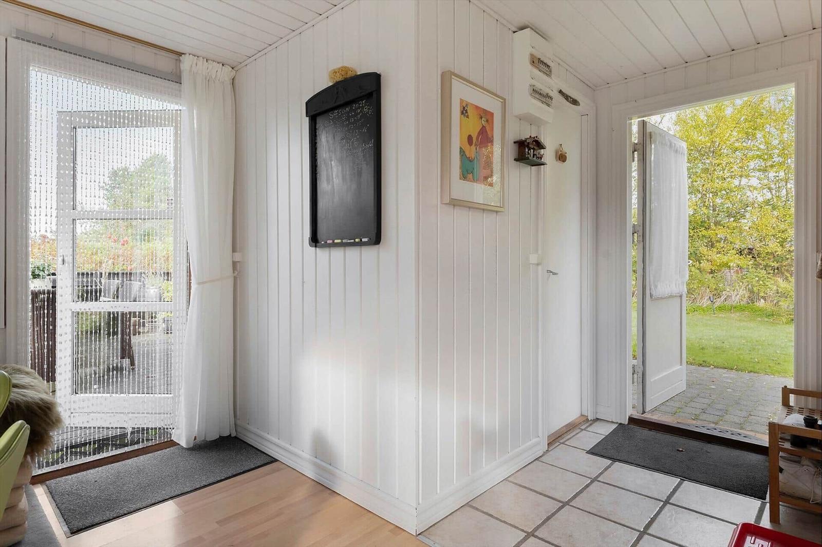 Entrance area with white walls, door to garden and balcony, map and picture on wall.