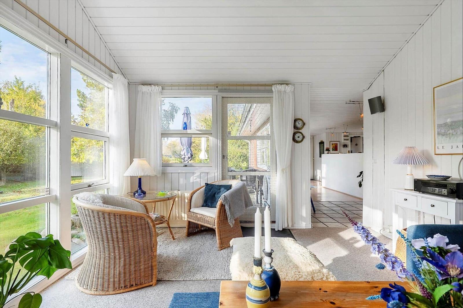 Living area with wicker chairs, large windows, and garden view.