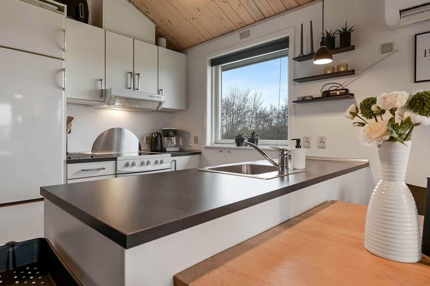 Küche mit Arbeitsplatte, Spüle und Fenster zum Blick nach draußen.