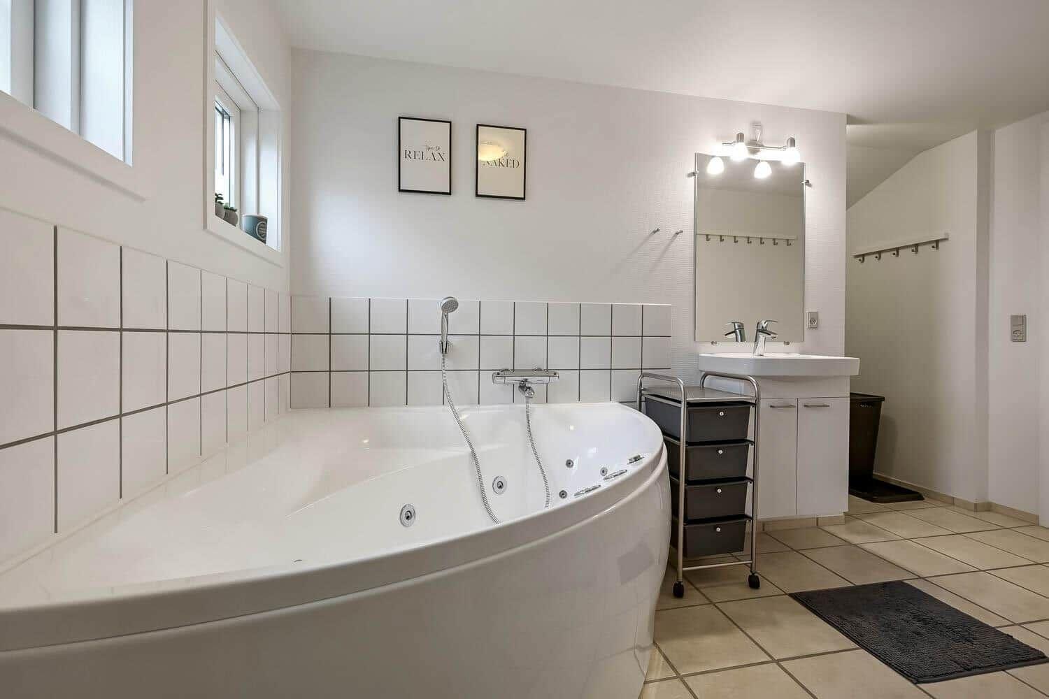 Badezimmer mit Whirlpool, Waschbecken und Spiegel.