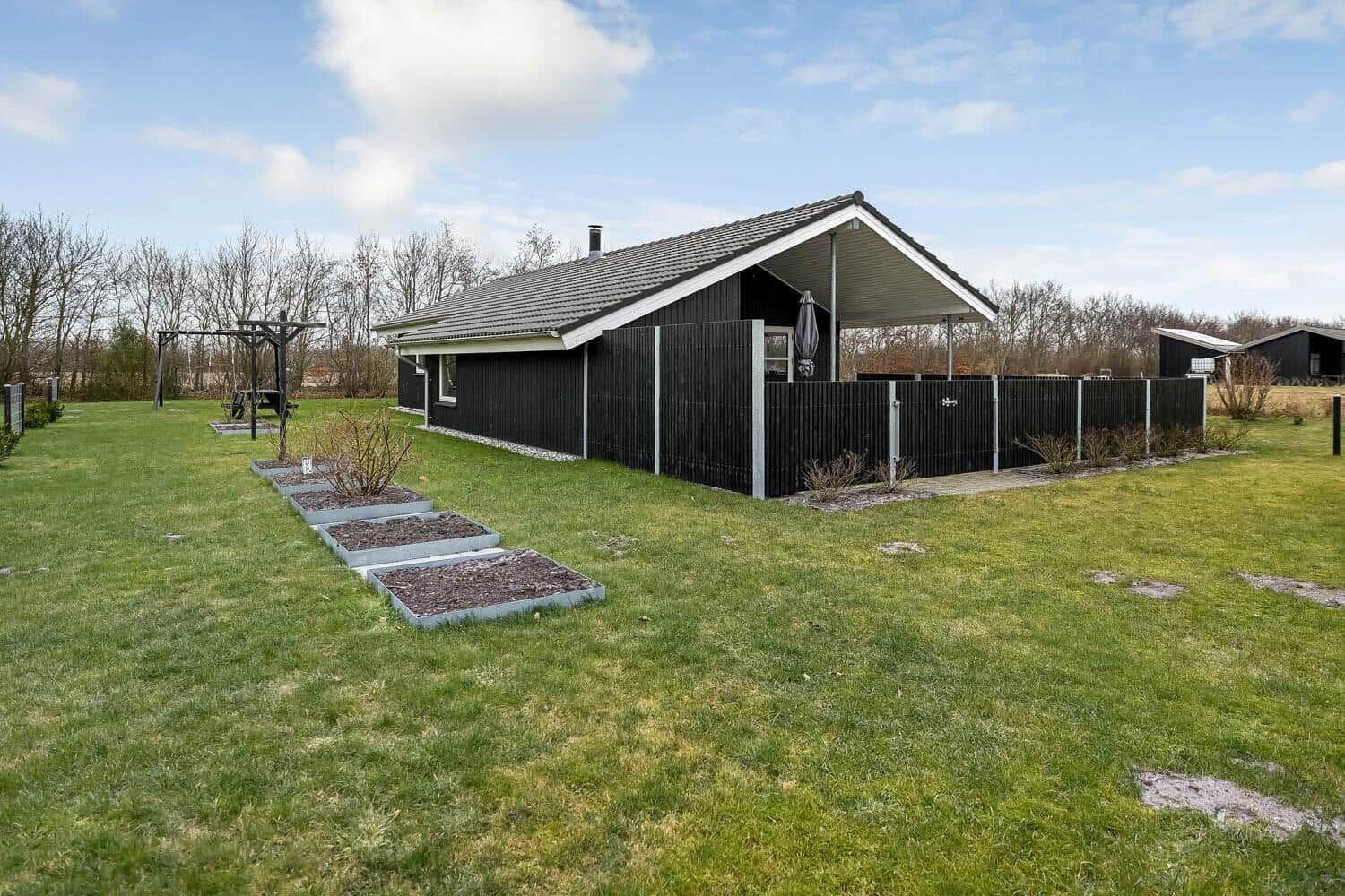 Schwarzes Ferienhaus mit Garten und Grillplatz.