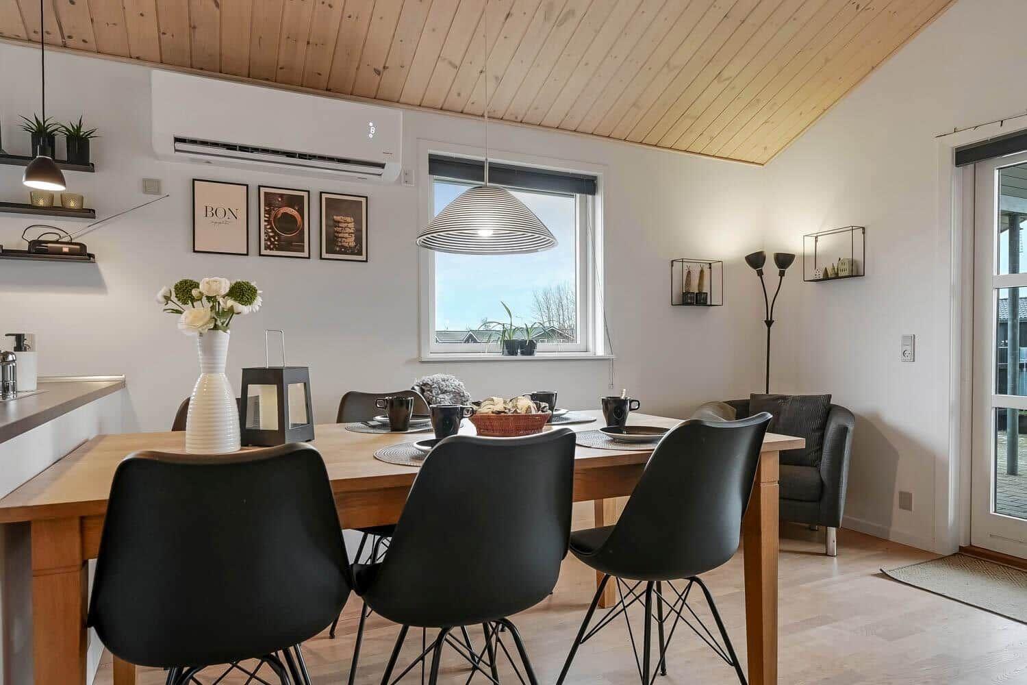 Essbereich mit Holztisch, schwarzen Stühlen und Fensterblick.