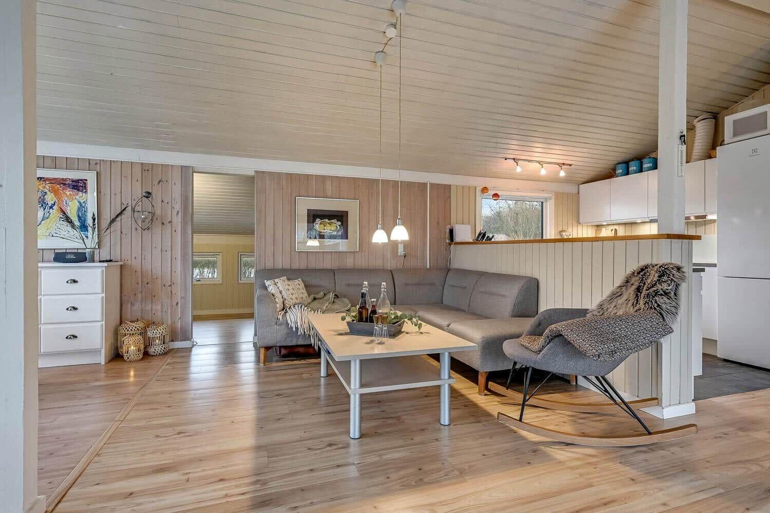 Wohnzimmer mit Sofa, Schaukelstuhl und Küchenbereich