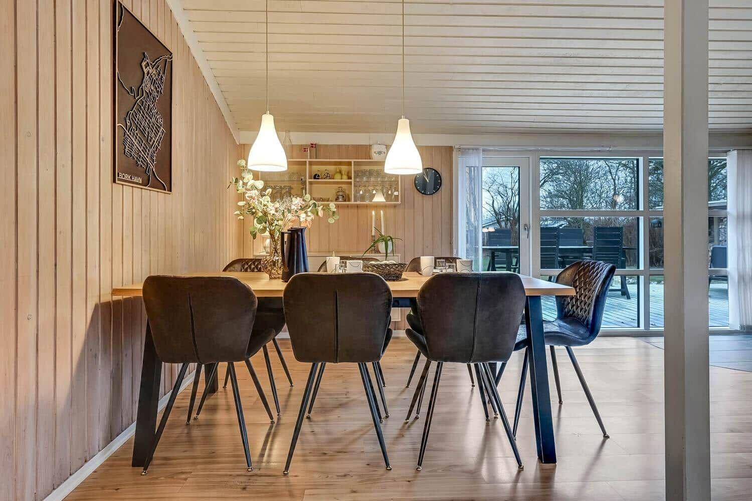 Esszimmer mit Holzwand, Tisch und Stühlen, Fenster zum Garten.