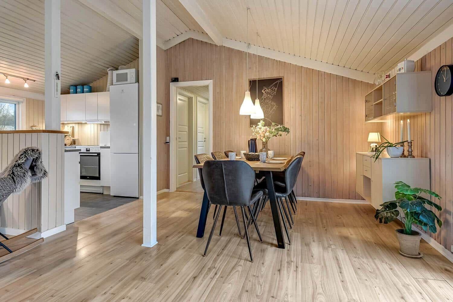 Essbereich mit Holzwand und Tisch. Küche im Hintergrund sichtbar.