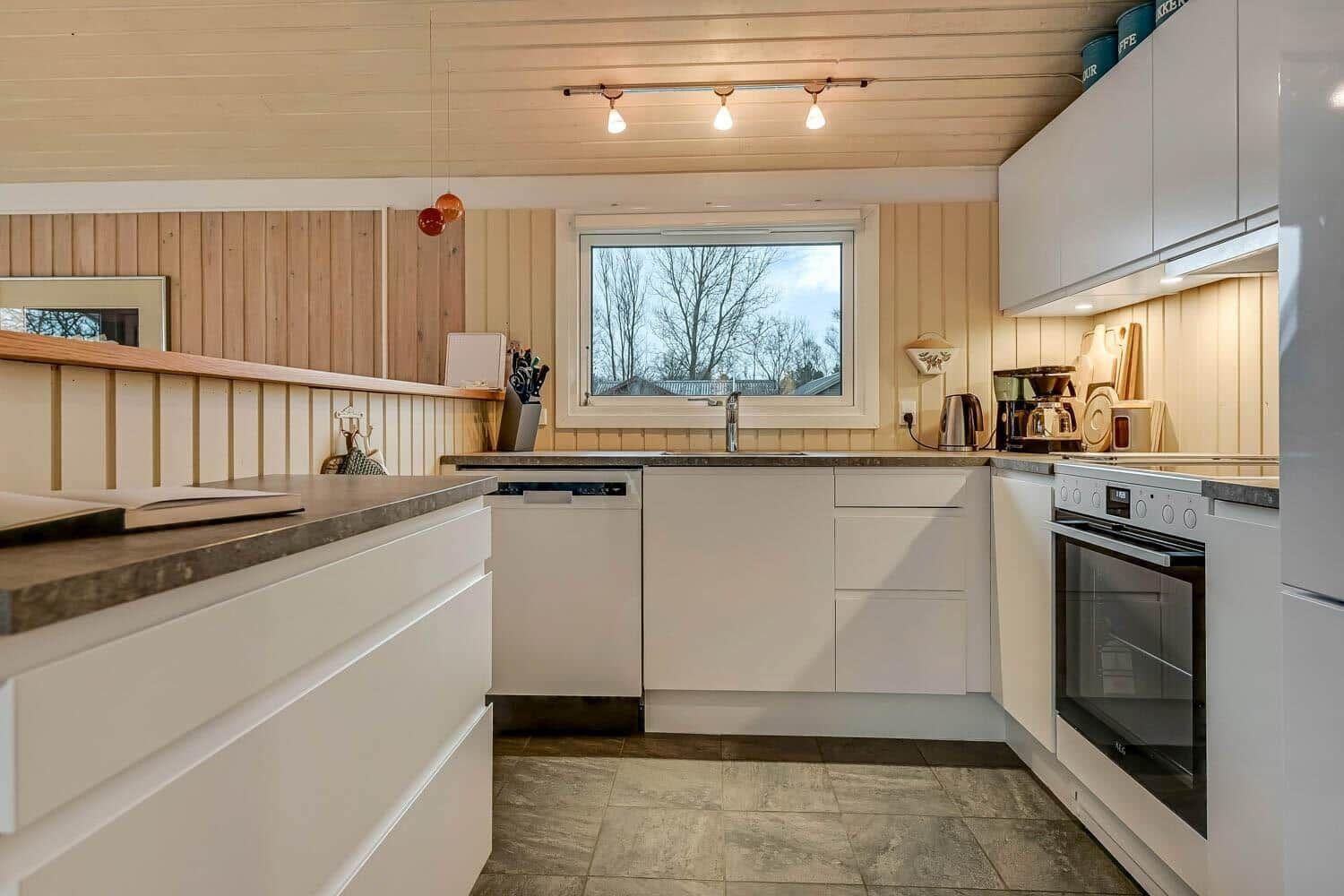 Moderne Küche mit weißen Schränken, Arbeitsplatte und Fenster.