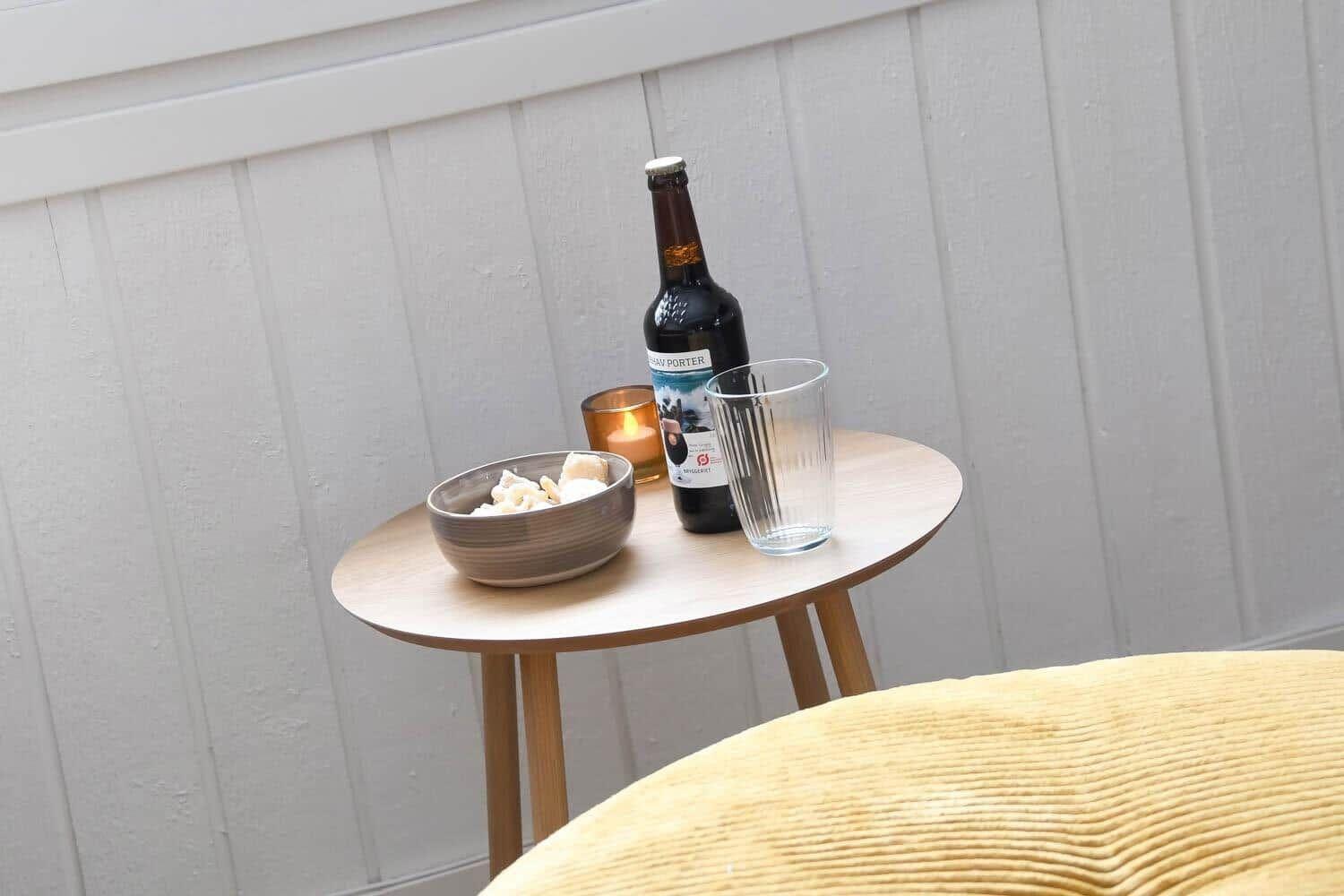 Runde Tisch mit Bier, Gläser und Schale vor weißer Wand