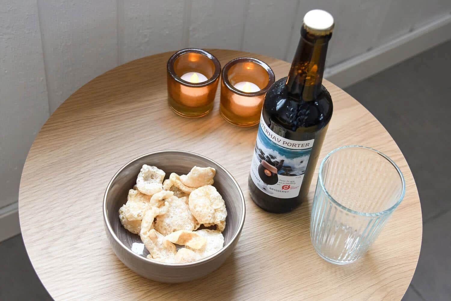 Runde Tisch mit Kerzen, Bier, Gläser und Schale mit Chips.