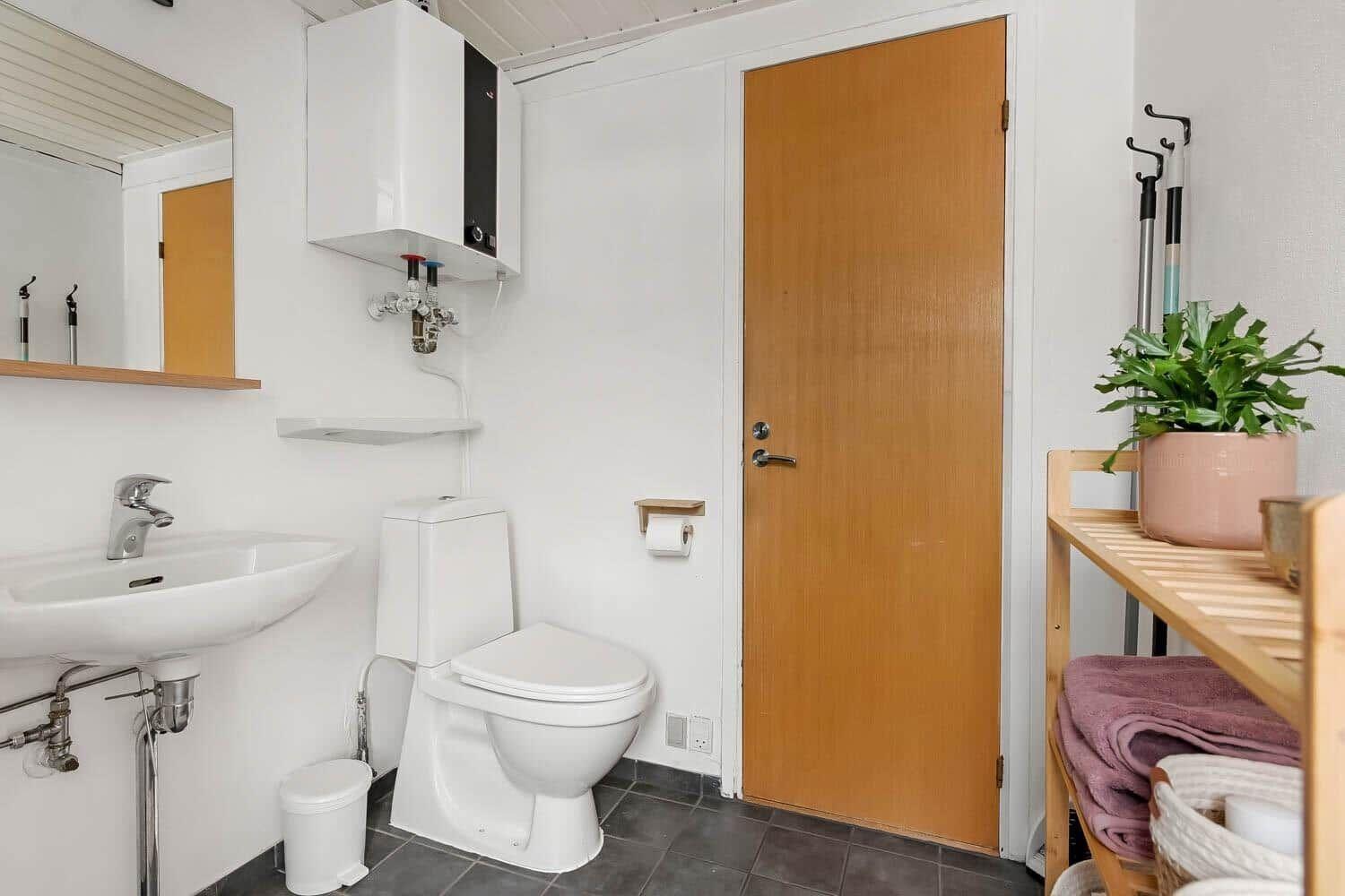 Badezimmer mit Toilette, Waschbecken und Holztür