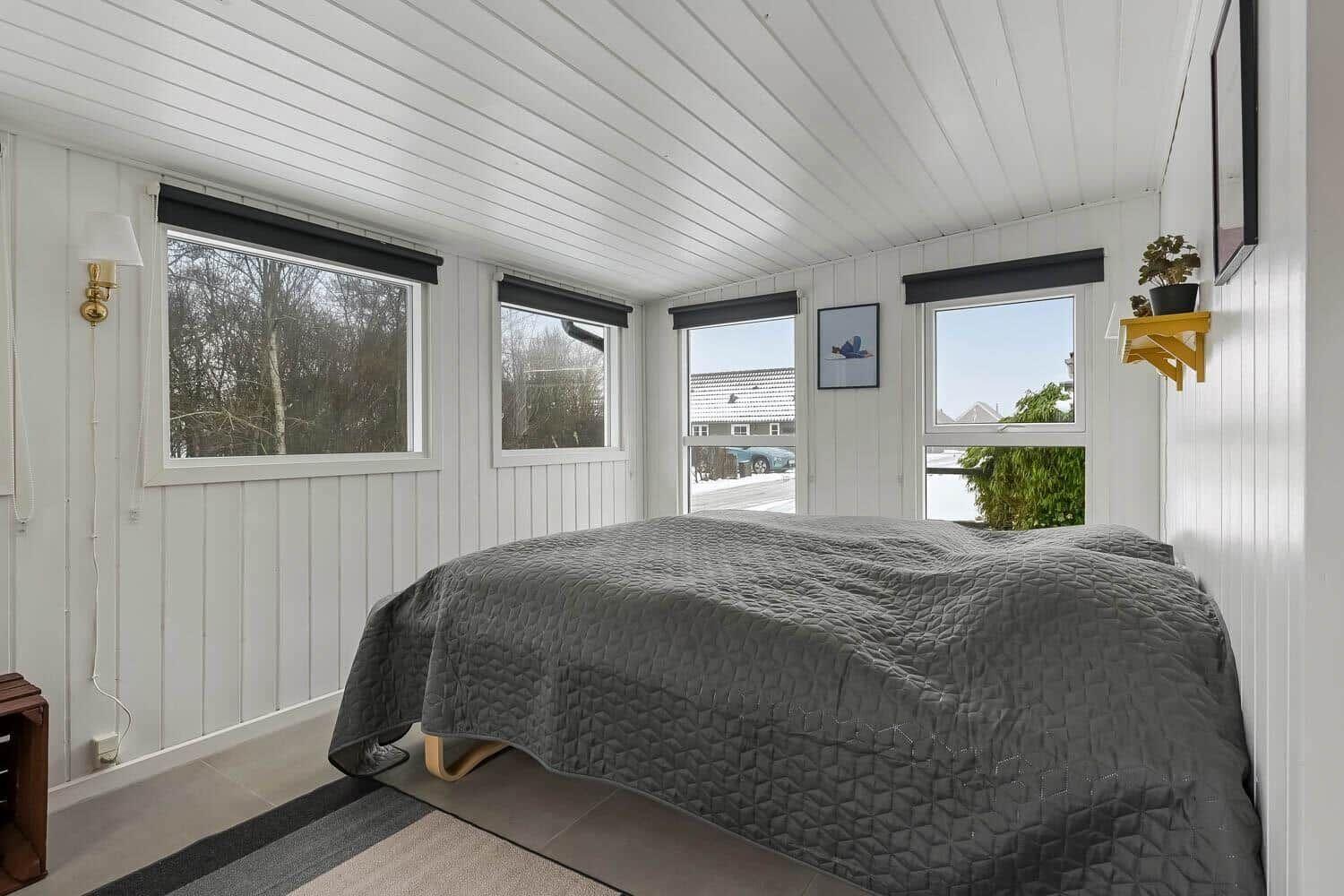 Schlafzimmer mit Bett, Fenstern und Wanddekoration.