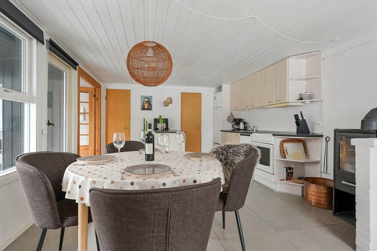 Essbereich mit Tisch, Stühlen und Küchenbereich. Decke mit Holzverkleidung und Pendelleuchte.