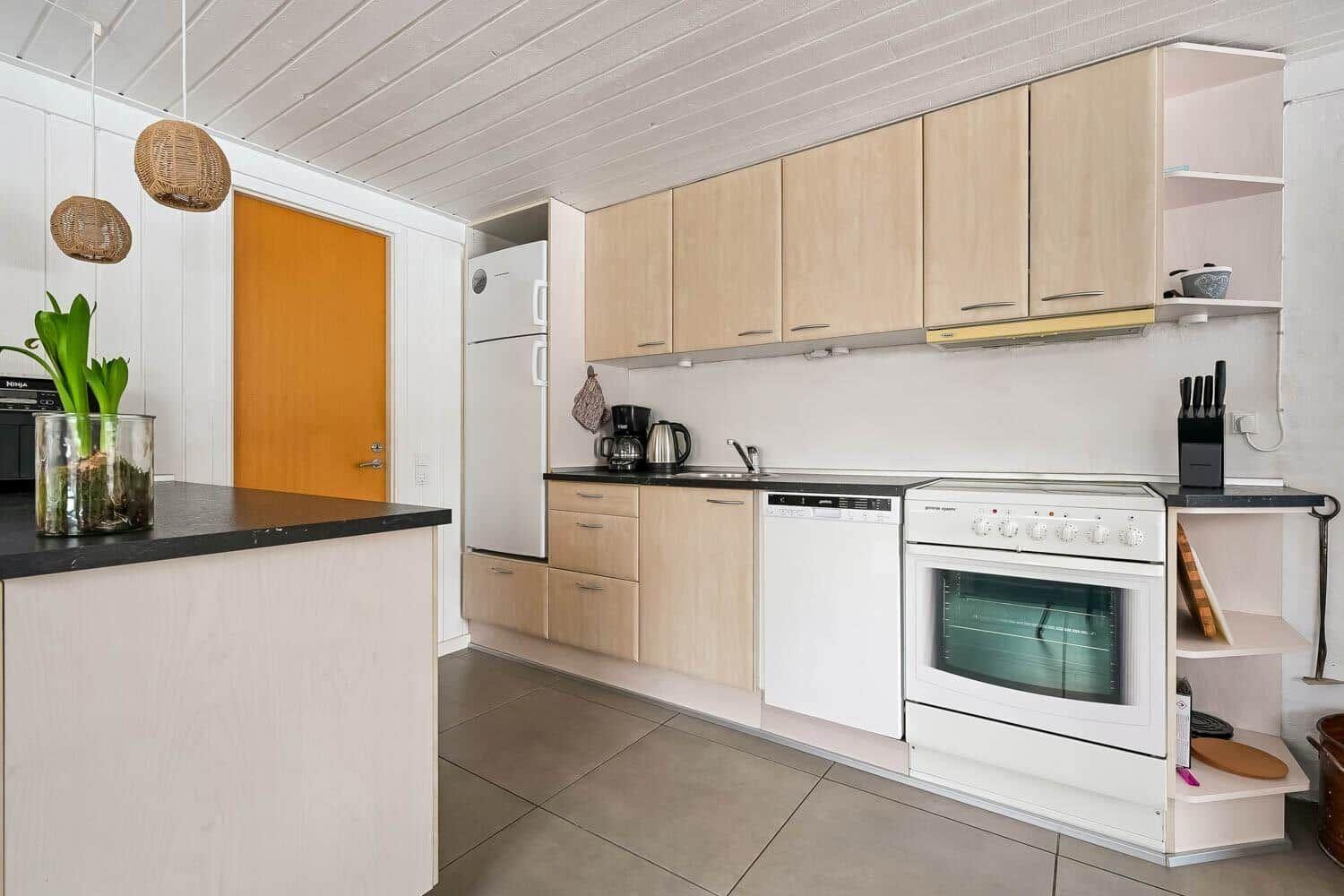 Küche mit Holzschränken, Kühlschrank, Spüle und Kochfeld.