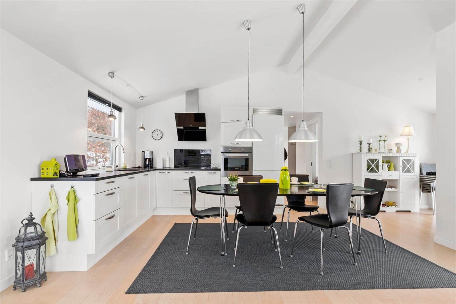 Kitchen and dining area with black chairs and white built-in kitchen.