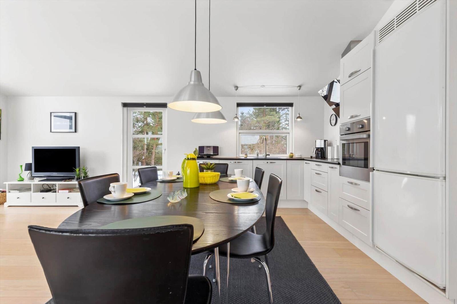 Kitchen with dining table, white cabinets, and view to outdoor terrace.