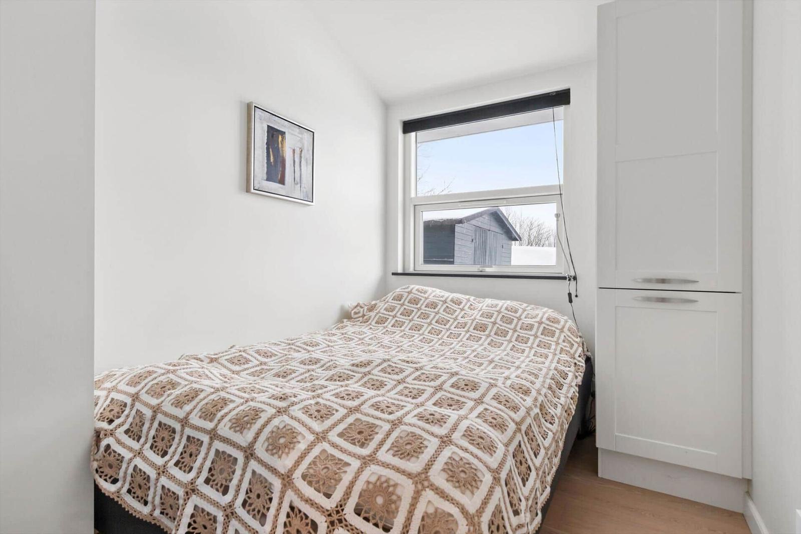 Bedroom with bed, window, and white cabinets.