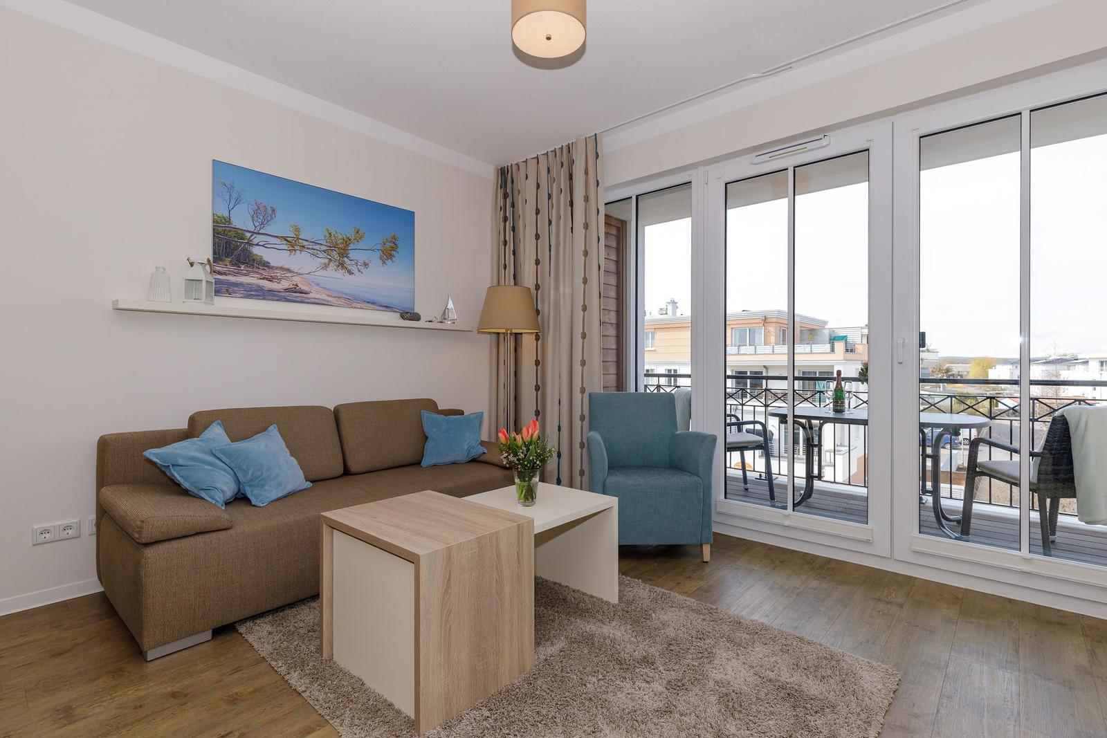 Wohnzimmer mit Sofa, Sessel und Balkon. Holzboden und Wandbild.