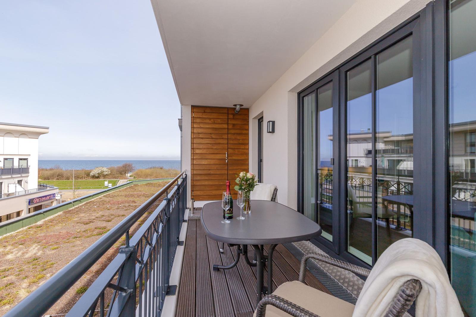 Terrasse mit Tisch, Stühlen und Meerblick.