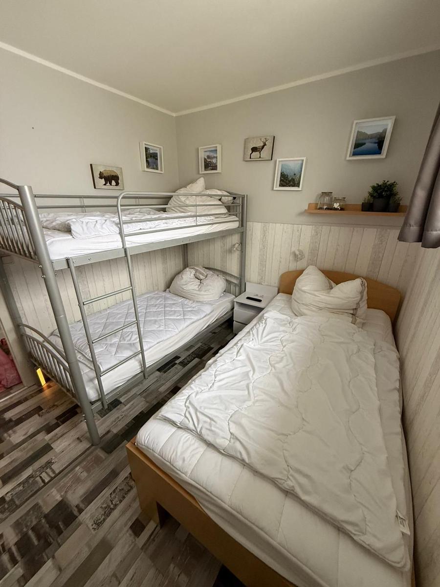 Zimmer mit Doppelstockbett und Einzelbett, Wandbilder und Holzpaneelen.