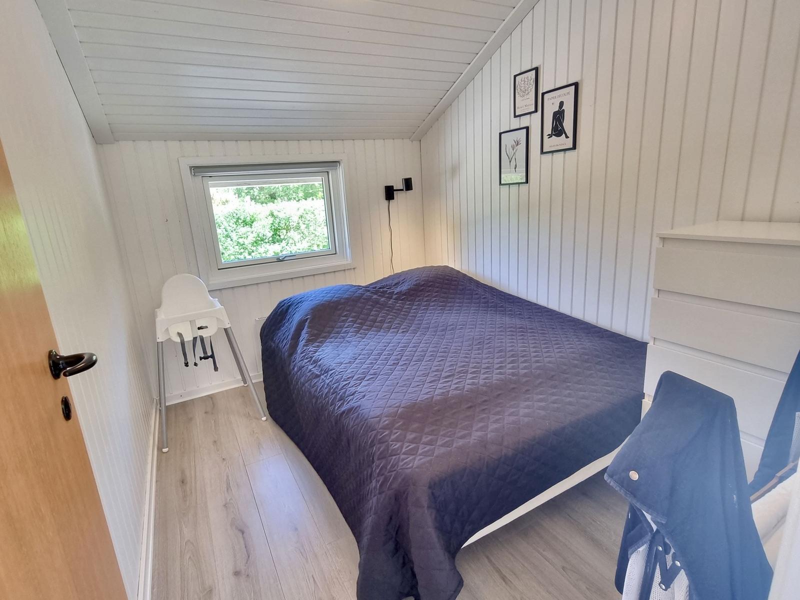 Schlafzimmer mit Bett, Fenster und Kleiderständer