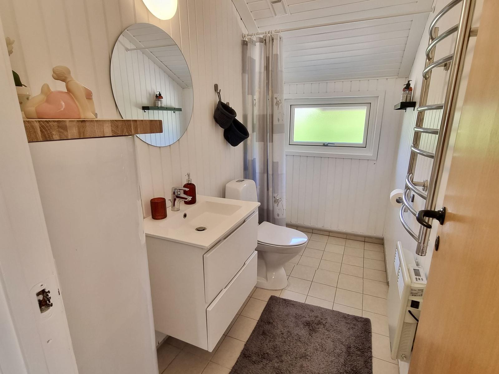 Badezimmer mit Waschbecken, Toilette und Dusche. Weiße Wände und Fliesen.