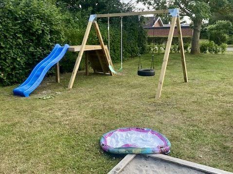 Hinterhof mit Holzspielplatz, Rutsche und aufblasbarem Pool.