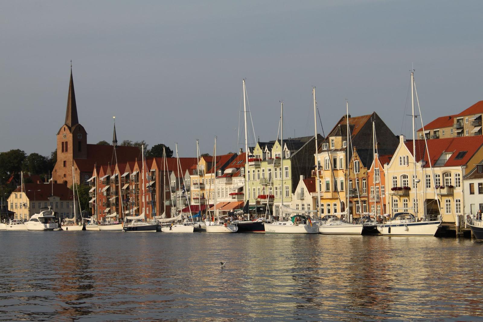 Hafen mit Booten und farbigen Häusern. Kirche im Hintergrund.