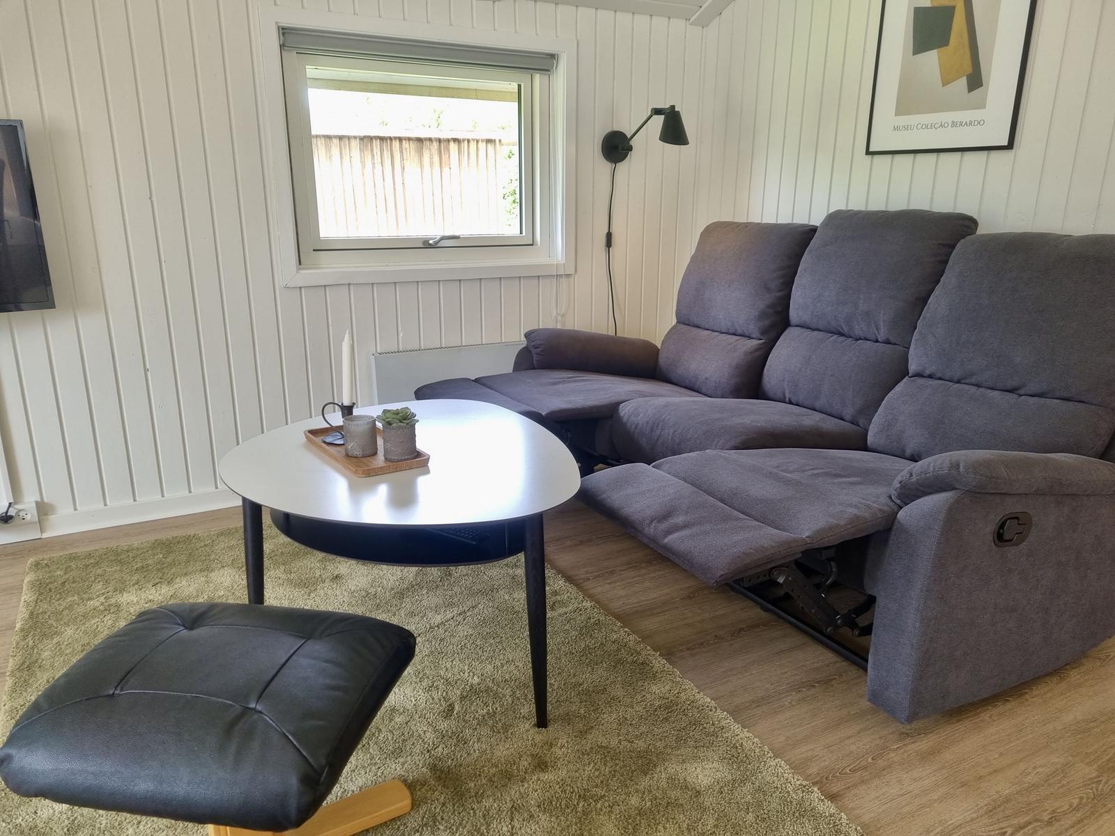 Ein Wohnzimmer mit grauem Sofa, runder Tisch und Teppich.