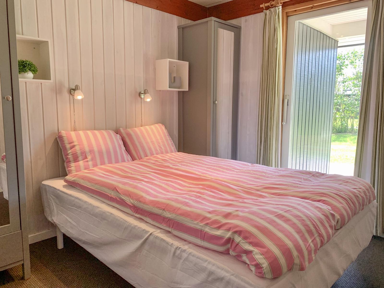 Schlafzimmer mit Bett, Schrank und Schlafzimmerausgang.