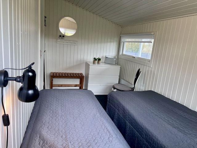 Zwei Betten, Schreibtisch, Spiegel und Fenster in einem Schlafzimmer.