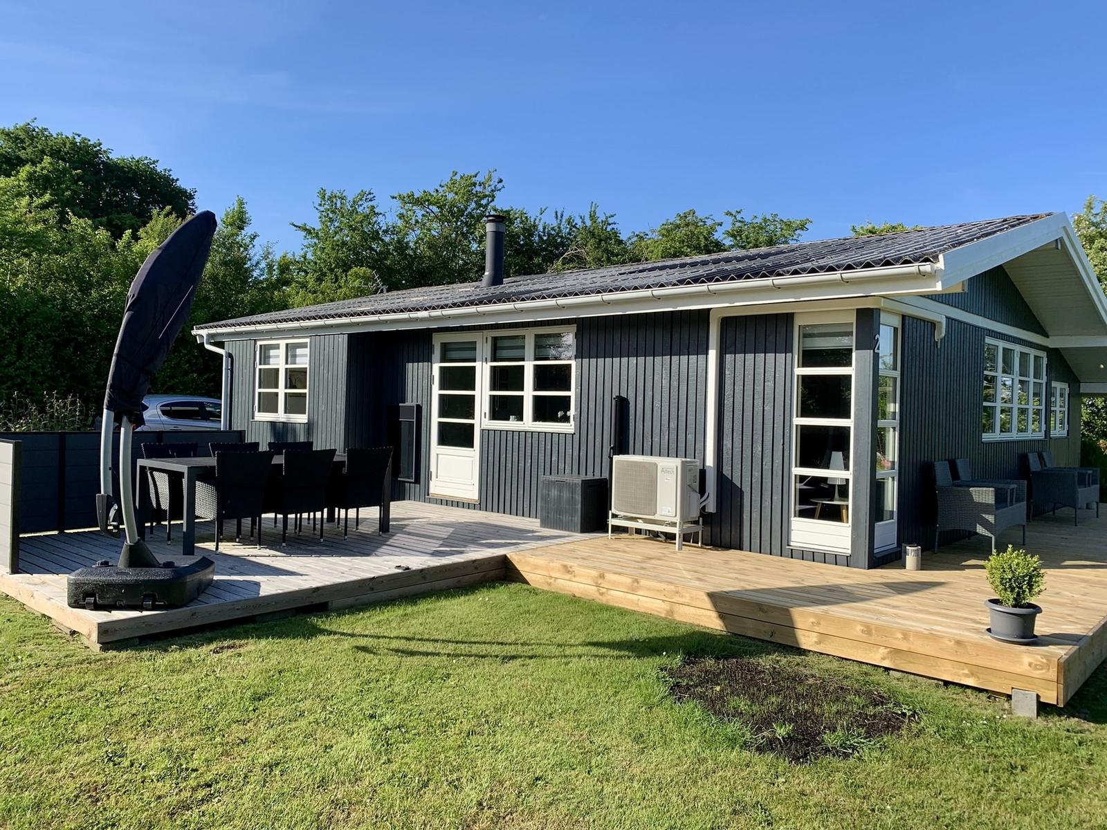 Ein Ferienhaus mit Terrasse, Garten und Außensitzgelegenheiten.