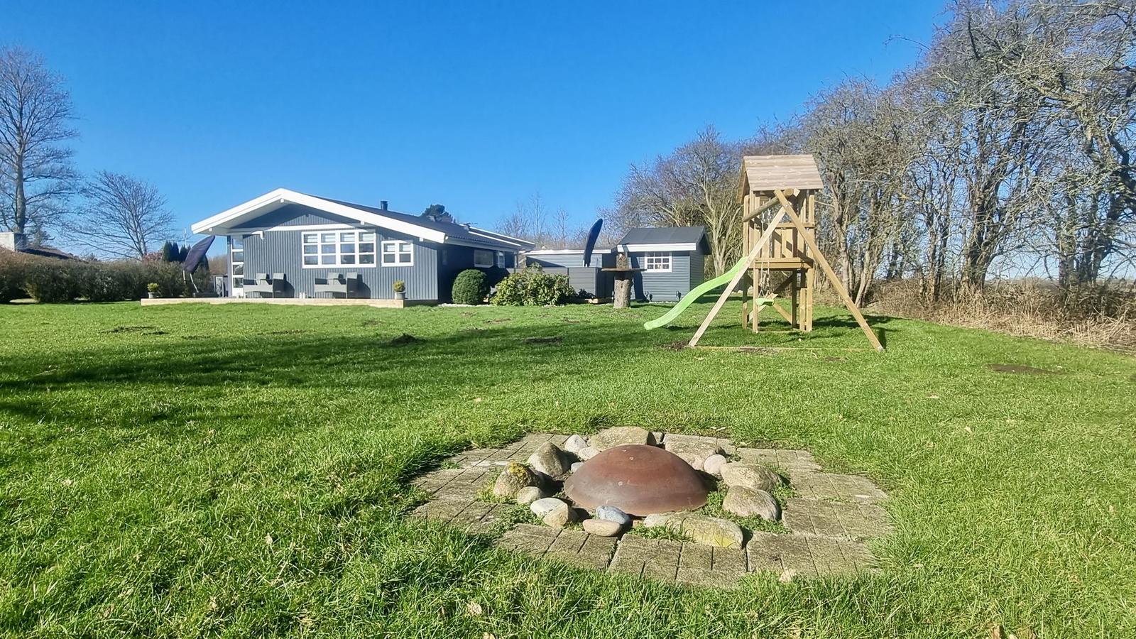 Haus mit Spielplatz und Grillplatz im Garten.