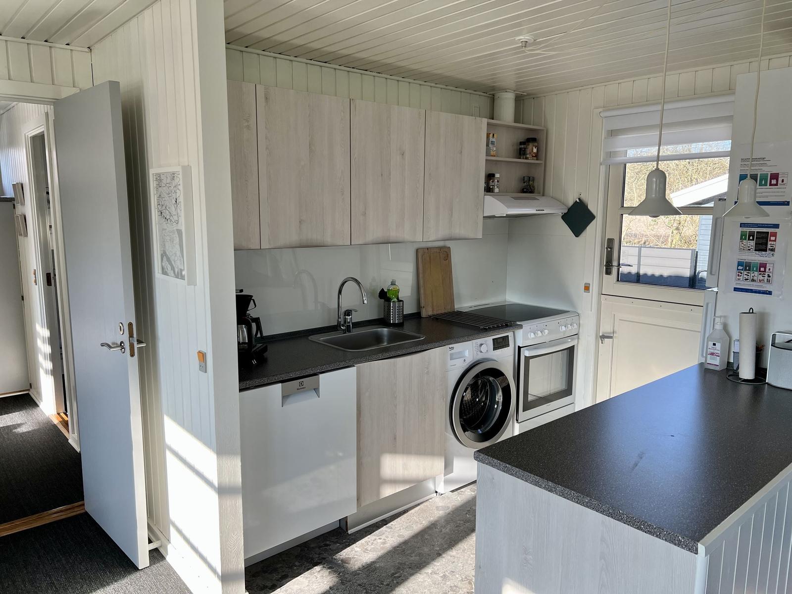 Küche mit Spüle, Kochfeld, Waschmaschine und Arbeitsplatte.